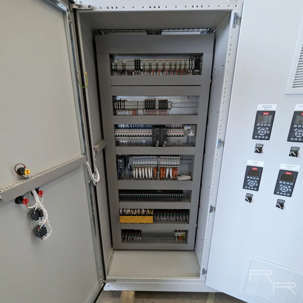 Control section internals with terminal rails, safety relays and PLC input and output modules