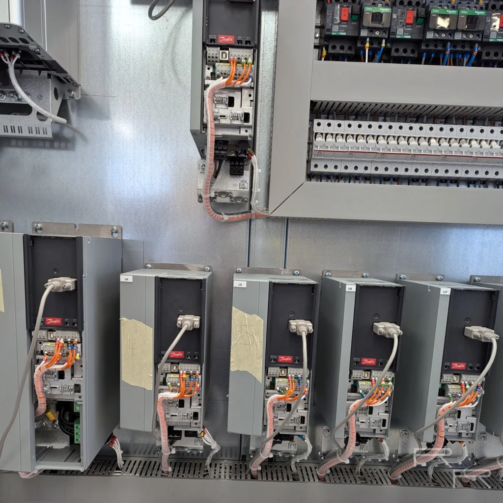 Bank of Danfoss VLT AQUA Drive variable speed drives mounted on the enclosure backplate