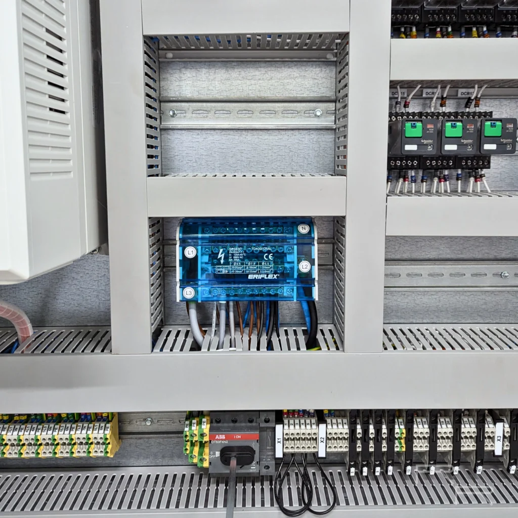 125A ERIFLEX four-pole distribution block above an ABB switch-disconnector and rows of numbered field terminal blocks