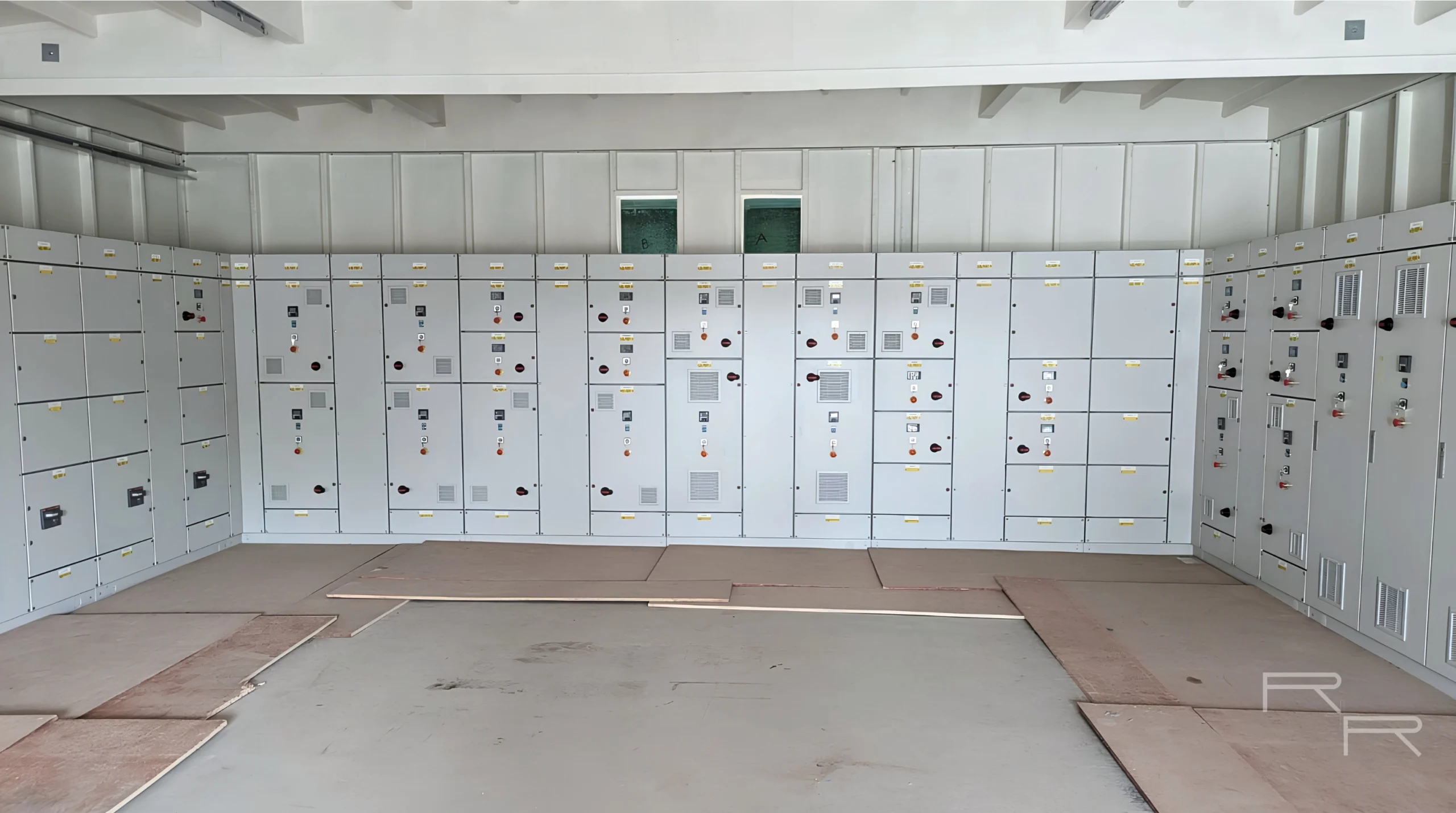 Multi-section motor control centre installed in a plant room, cubicle doors closed along three walls